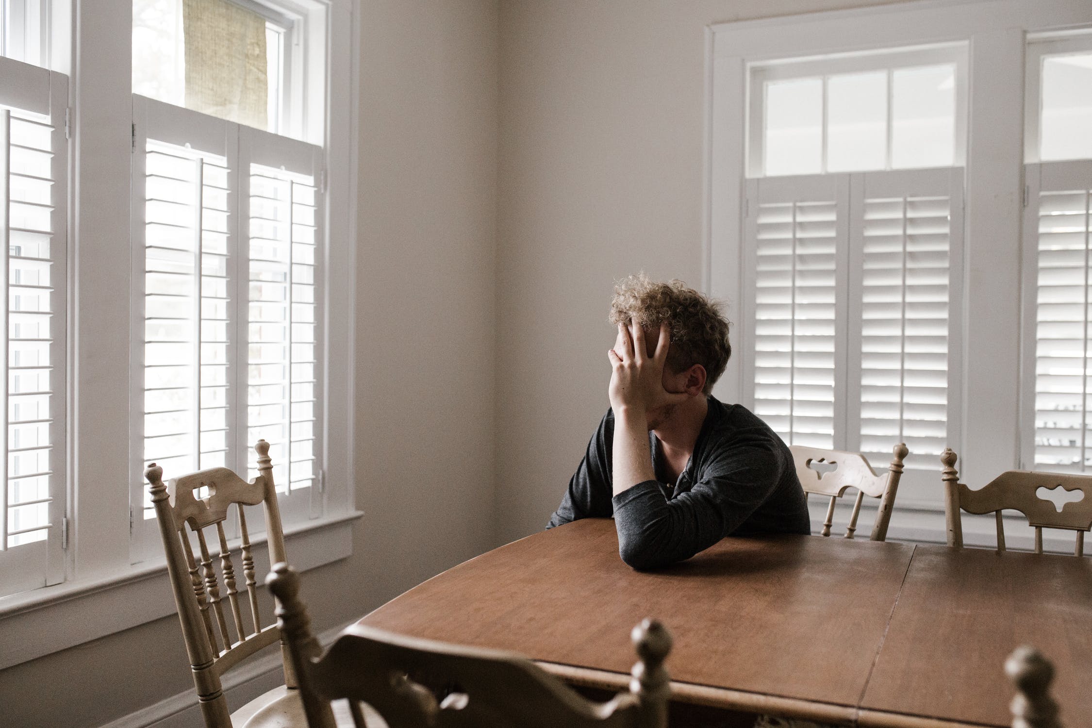 man sitting at kitchen table sad over being falsely accused of domestic violence in new jersey